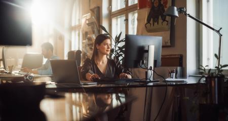 Woman sitting at a desk looking at a computer monitor